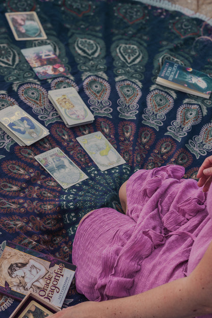 Spiritual lady knees and pulls tarot cards on a spiritual blanket. 