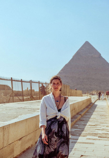 Woman standing in front of a pyramid with a clear blue sky
